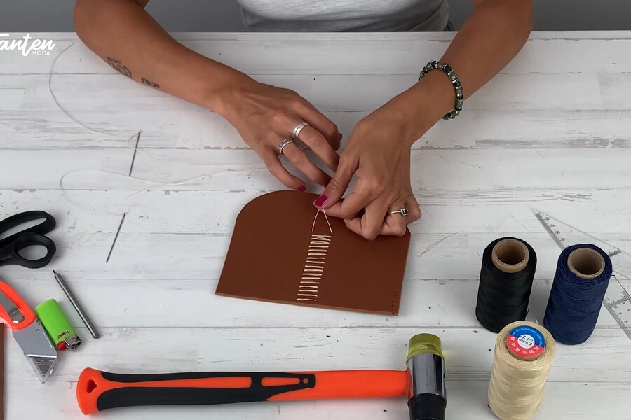 Manos cosiendo cuero a mano con dos agujas formando la X interior del saddle stitch — Método Tanten